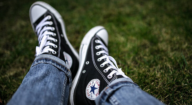 black classic high top converse all star shoes paired with jeans against grass background